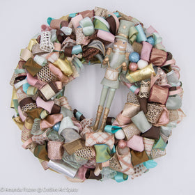 The Cre8ive Art Space Pastel Nutcracker Wreath is full of soft hues that twinkle in the light.   The glittering ribbon choices complement the warn tones. Crafted in the USA
